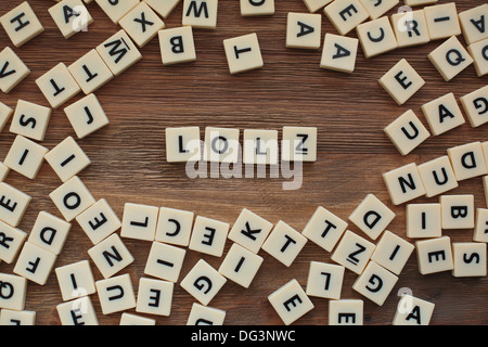 Plastic letters from a childrens' spelling game on a wooden table spell 'LOLZ' Stock Photo