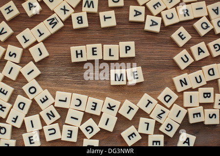 Plastic letters from a childrens' spelling game on a wooden table spell  'help me' Stock Photo