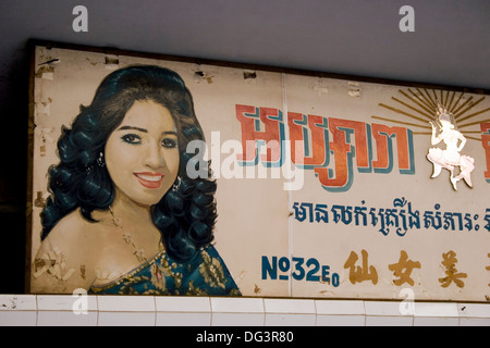 A painted sign showing a woman and written in Khmer and Chinese hangs above a beauty salon  in Phnom Penh, Cambodia. Stock Photo