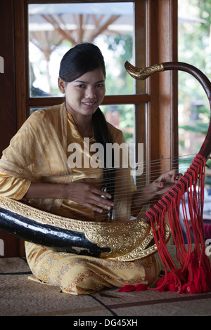 Girl playing traditional saung gauq (boat shaped harp) at Popa Mountain Resort, Mount Popa, near Bagan, Myanmar Stock Photo