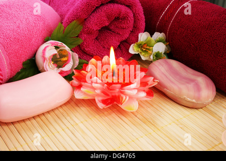 Towels, soaps, flowers and candles on mat background. Stock Photo