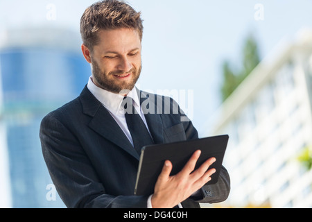 A smart young businessman with a beard using a tablet computer Stock Photo