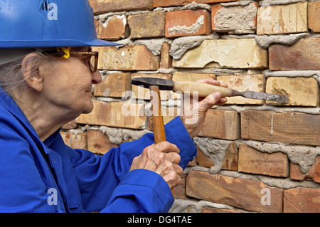 Elderly woman holding a hammer and chisel. Construction background Stock Photo