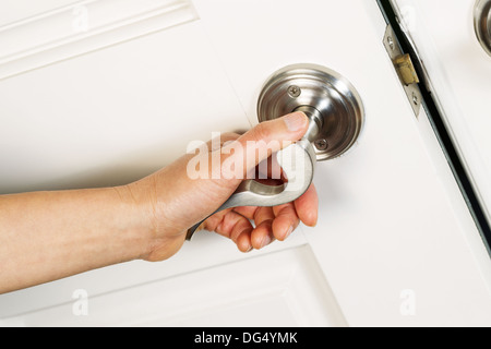 Angled horizontal photo of female hand turning door handle, to open, on front door of house Stock Photo