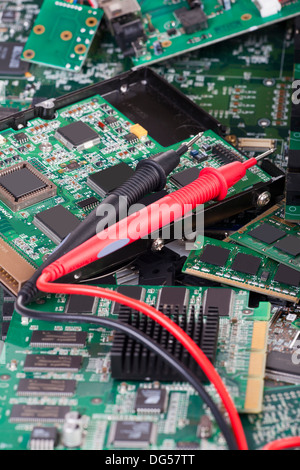 Measuring tips of a digital multimeter are on many circuit boards Stock Photo