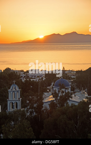 CYCLADES, GREECE. Sunrise over the Aegean island of Anafi, as seen from the resort of Kamari on Santorini (Thira). Stock Photo