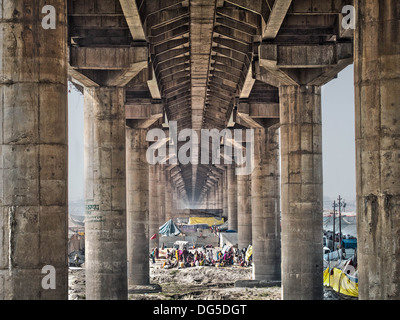 People and tents under the main bridge crossing over the massive Kumbh Mela 2013 festival in Allahabad, India. Stock Photo