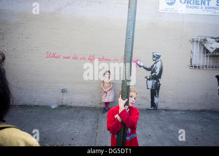 New York, USA. 14th Oct, 2013. Parents bring their children to the Woodside neighborhood of Queens in New York on Monday, October 14, 2013 to see the fourteenth installment of Banksy's graffiti art, 'What we do in life echoes in Eternity'. The elusive street artist is creating works around the city each day during the month of October accompanied by a satirical recorded message which you can hear by calling the number 1-800-656-4271 followed by  # and the number of artwork.  (© Richard B. Levine) Credit:  Richard Levine/Alamy Live News Stock Photo