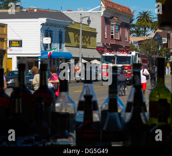 A fire engine screams down Bridgeway in downtown Sausalito, California as seen through a bar window. Stock Photo