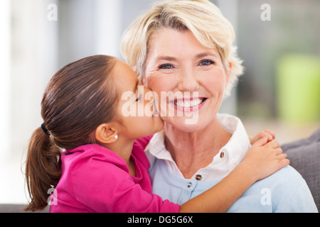 loving cute granddaughter kissing her grandmother at home Stock Photo