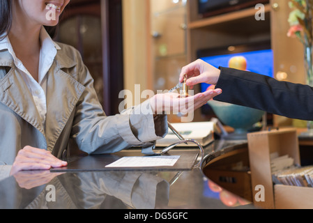 female guest being handed over the keys to hotel room by receptionist, travel and tourism concept Stock Photo