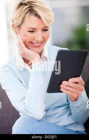 attractive mature woman reading a book on tablet computer Stock Photo