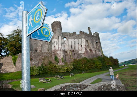 View of Laugharne Castle with a Welsh coast path sign the town of Laugharne, , Wales UK Stock Photo