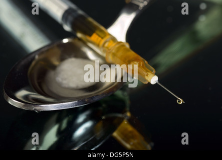 Syringe with drop and spoon, concept of drug addiction Stock Photo