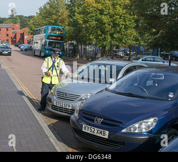 Traffic warden attaching ticket to car in Buckingham, England, UK Stock Photo