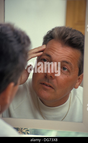 middle aged man looking in mirror Stock Photo