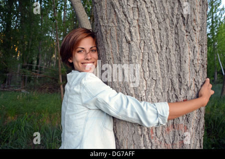 Young attractive woman hugging a tree in nature Stock Photo