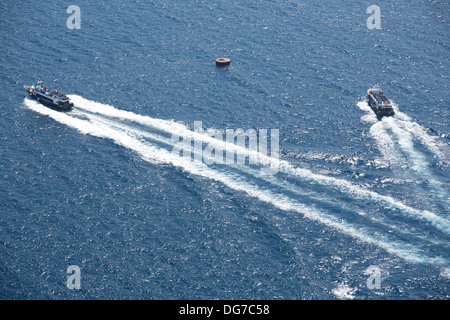 Two little Ferry boats in the blue Aegean sea in front of the island of Santorini. Stock Photo