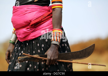 A pregnant Rendille woman holding her machete while looking after some goats, near Marsabit, Kenya Stock Photo