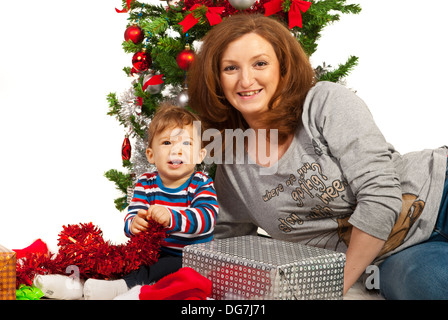 Happy Christmas mother and her baby sitting under tree Stock Photo