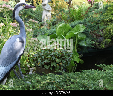 Plastic heron guarding a garden pond Stock Photo