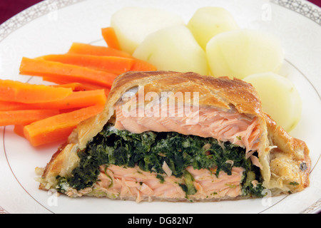 Salmon fillet stuffed with a spinach mixture and encased in puff pastry, served with boiled new potatoes and julienned carrots. Stock Photo