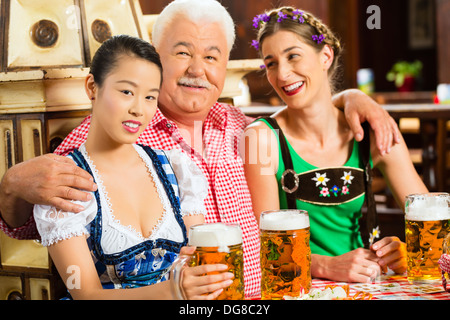 In Pub - friends in Tracht, Dirndl and Lederhosen drinking a fresh beer in Bavaria, Germany Stock Photo