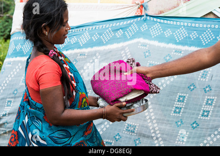 Lower caste Indian pregnant teenage girl receiving free food and clothes outside her bender / tent.  Andhra Pradesh, India Stock Photo