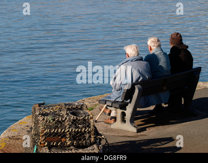 Three old men sat on a bench at the seaside, Bude, Cornwall, UK Stock Photo