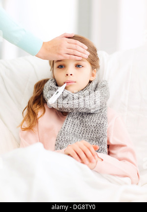 ill girl child with thermometer and caring mother Stock Photo