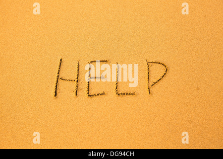 Help - written in sand on beach texture. Stock Photo