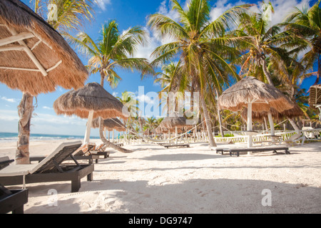 Chaise lounges under an umbrella on sandy beach Stock Photo