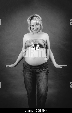 beautiful smiling pregnant woman with child boots on her tummy Stock Photo