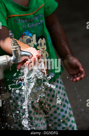 Young Indian girl / infant playing with water from a tap in a rural Indian village. Andhra Pradesh, India Stock Photo