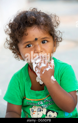 Young Indian girl / infant eating ice cream in a rural indian village. Andhra Pradesh, India Stock Photo