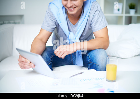Image of young guy in casual sitting on sofa and using touchpad Stock Photo