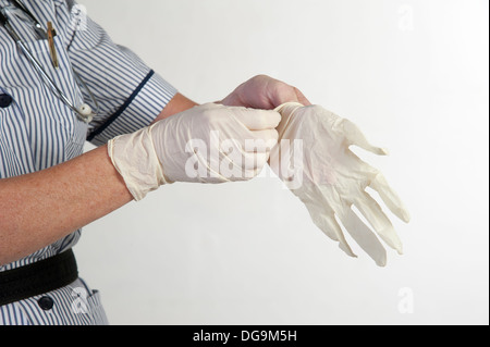 Female nurse pulling on rubber surgical gloves Stock Photo