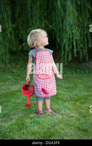 little girl with watering can, outdoors in the garden Stock Photo