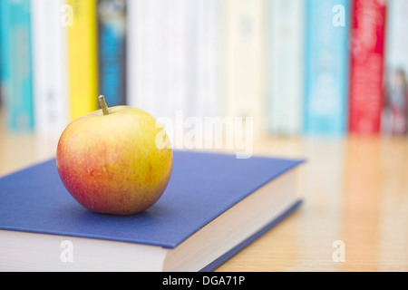 Book with ripe apple a nd row of books in background Stock Photo