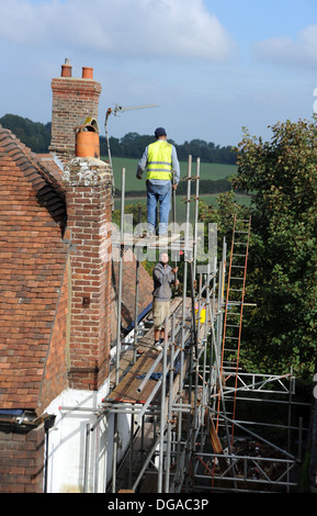Builders working on scaffolding repairing roof on old historic house in Battle High Street Sussex UK Stock Photo
