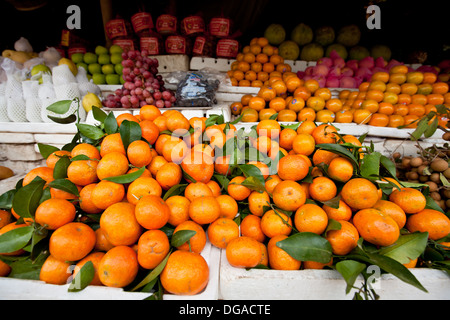 A local street  market filled selling produce, fruits including tangerines piled in heap on table in Siem Reap, Cambodia Stock Photo