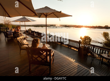 Guests on the Sunset verandah watching the sunset over the Zambezi River, Royal Livingstone Hotel, Zambia Africa Stock Photo