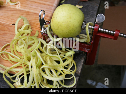Green apple on an apple peeler, with apple peelings Stock Photo