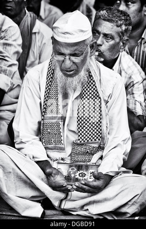 Indian Muslim man in prayer whilst waiting to be seen at Sri Sathya Sai Baba mobile outreach hospital. Andhra Pradesh, India Stock Photo