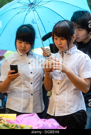 Young ladies in office uniform check their mobile phones Stock Photo