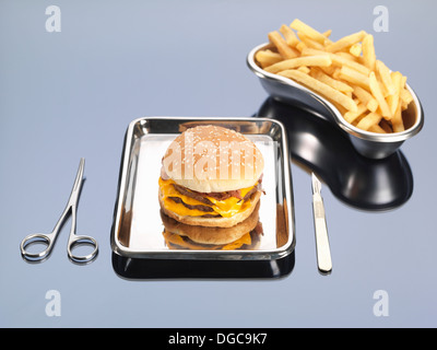 Burger and fries sitting in surgical trays illustrating unhealthy diet Stock Photo