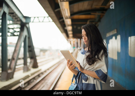 Mid adult women using digital tablet on subway platform, Brooklyn, New York
