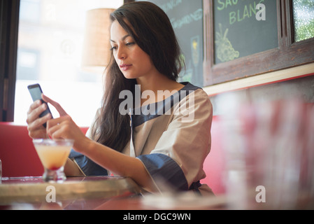 Mid adult women using mobile phone in restaurant Stock Photo