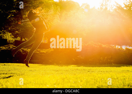 Young female jumping mid air in park Stock Photo