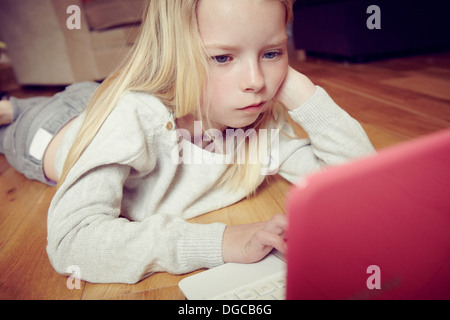 Young girl lying on floor using laptop Stock Photo